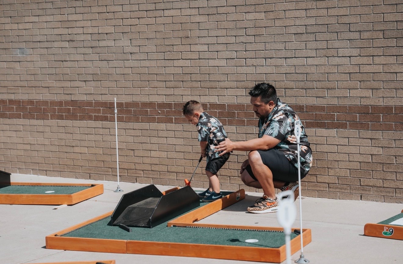 Dad showing daughter how to play mobile mini golf 